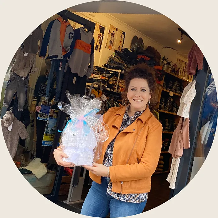 In de deuropening van de winkel met een feestelijk ingepakt babycadeau