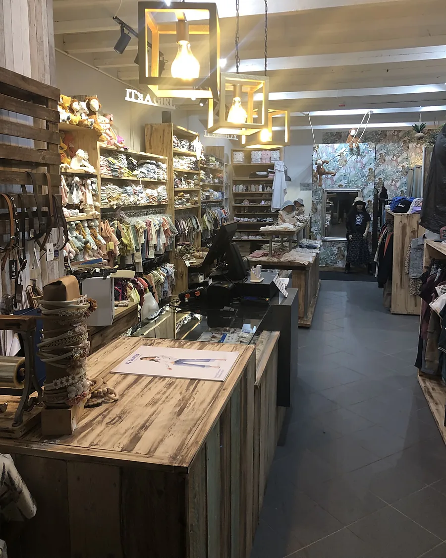 De toonbank van gebleekt hout en de kasten met babykleding